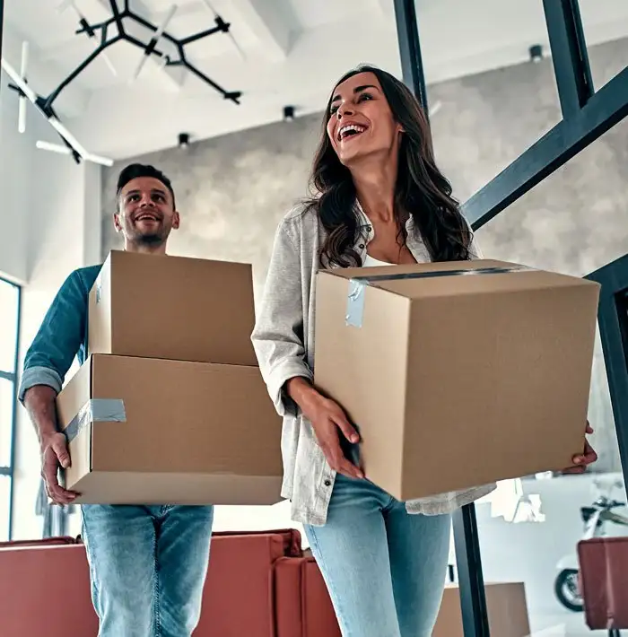 Couple carrying moving boxes into their new home